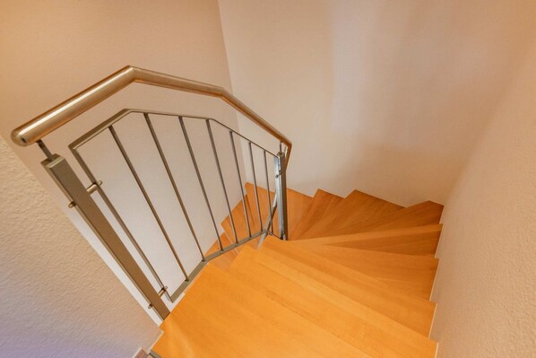 A wooden staircase with a metal handrail and a glass balustrade.