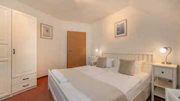 A bedroom with a double bed, bedside tables with lamps, a wardrobe, and a door.