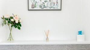 A bathroom with a white sink, a framed floral artwork above it, and a tiled backsplash.