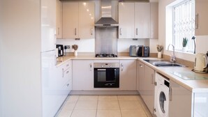 A modern kitchen with stainless steel appliances, a built-in oven, and a washing machine.