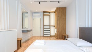 Un dormitorio moderno con una cama grande, un armario de madera y un vestidor.
