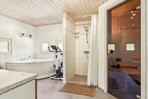 Ein modernes Badezimmer mit freistehender Badewanne, einer Duschkabine und Trainingsgeräten.