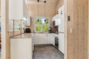 Eine moderne Küche mit Holzwänden, einem Fenster und Edelstahlgeräten.
