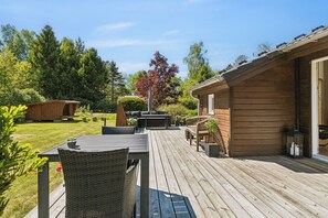 Eine Holzterrasse mit Gartenmöbeln, einem Whirlpool und einer Holzhütte.