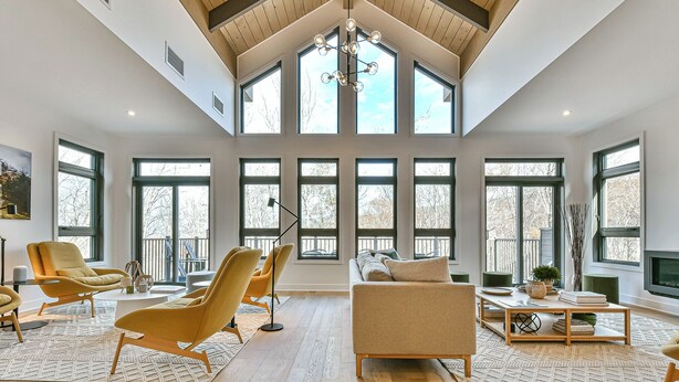 Ein großzügiges Wohnzimmer mit hohen Decken, großen Fenstern und modernen Möbeln.