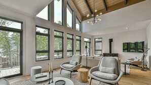 A spacious living room with large windows, modern furniture, and a high ceiling.