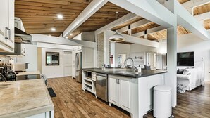 Una cocina amplia con pisos de madera, muebles blancos y una isla central.