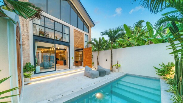 Ein modernes Haus mit Swimmingpool, großen Fenstern und einer Terrasse mit Sitzgelegenheiten.