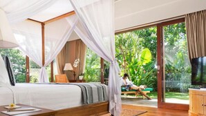 A bedroom with a canopy bed, a TV, and a view of the garden.