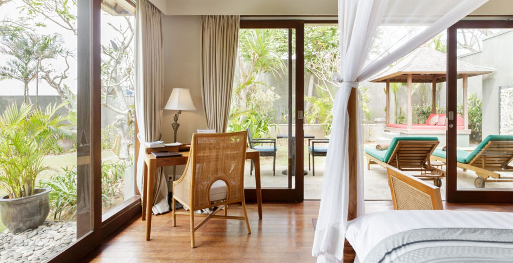Une chambre dotée d’un lit, d’un bureau et d’une chaise, avec vue sur une piscine et des chaises longues à l’extérieur.