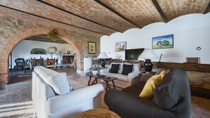 Een ruime woonkamer met een open haard, comfortabele zithoek en zichtbare bakstenen muren.