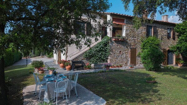 A stone building with a patio area, outdoor seating, and potted plants.