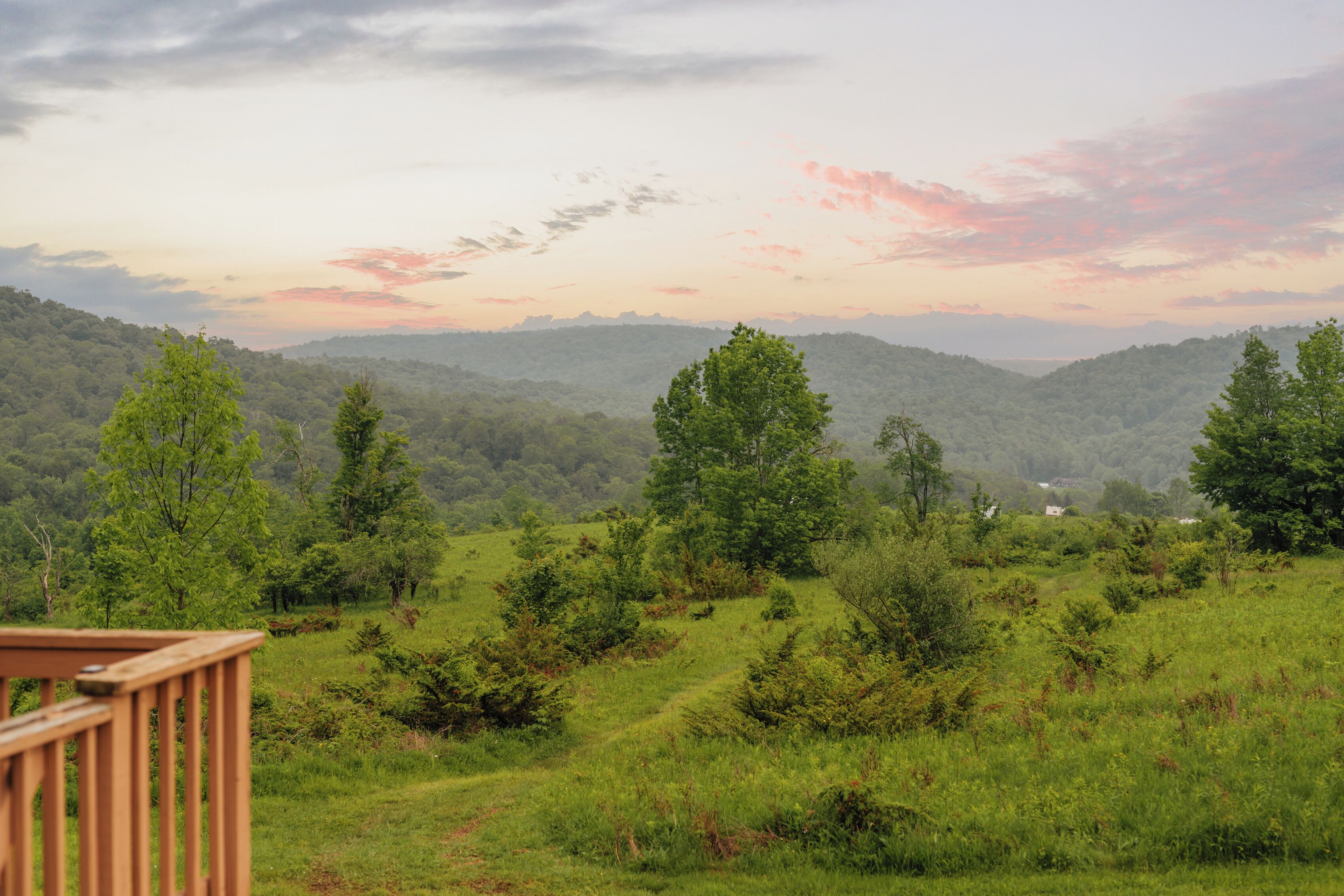 A scenic view of a lush green landscape with a wooden deck in the foreground.
