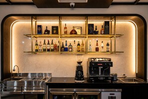 A bar area with shelves of liquor bottles, a coffee machine, and a sink.