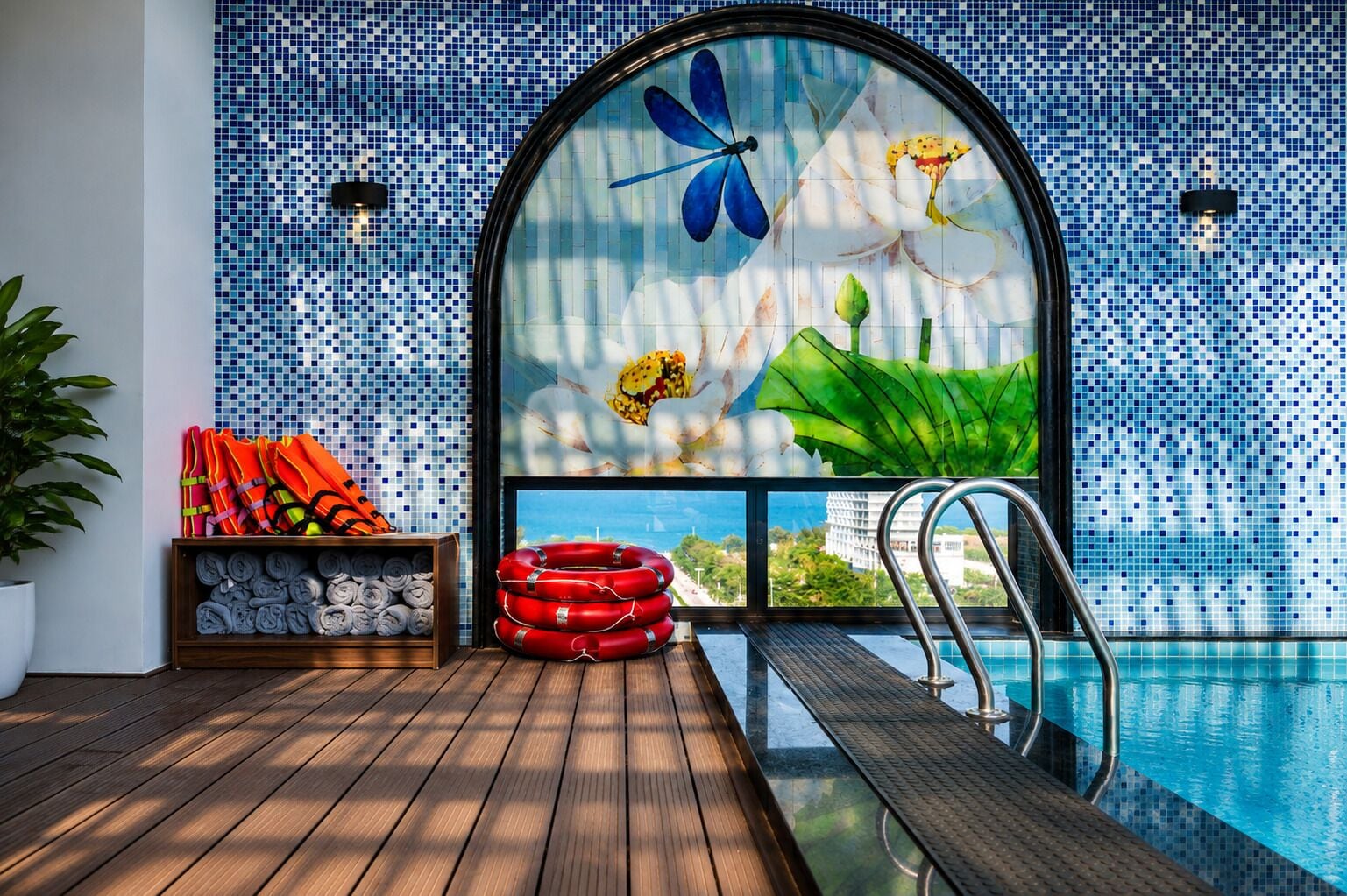 Un espace aménagé au bord de la piscine, avec une terrasse en bois, une bouée de sauvetage et une étagère contenant des serviettes.