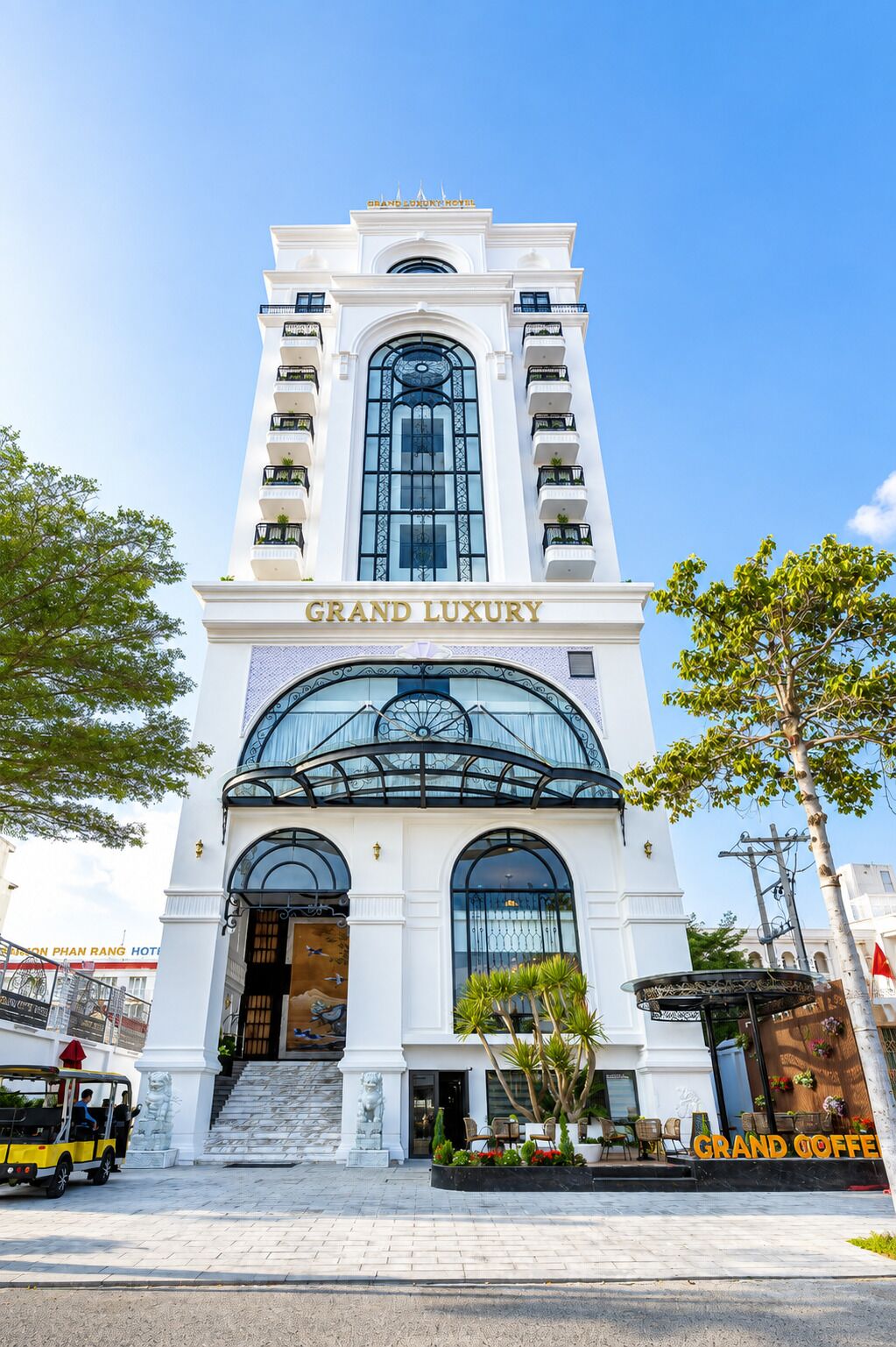 A grand hotel with a prominent entrance, a balcony, and a sign reading 'Grand Luxury'.