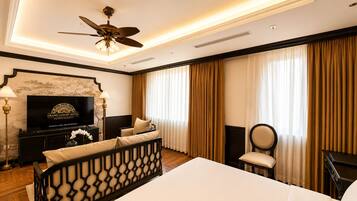A hotel room with a bed, a television, a desk, a chair, and a ceiling fan.
