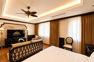 A hotel room with a bed, a television, a desk, a chair, and a ceiling fan.