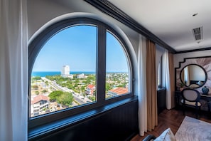A hotel room with a large arched window, a round mirror, a wooden floor, and a bed. - Grand Luxury Hotel Ninh Chu (Phan Rang - Thap Cham)