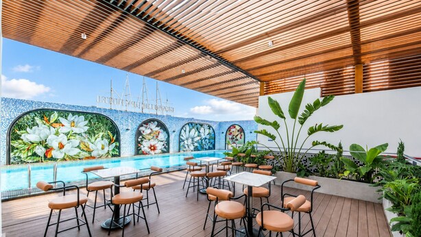 Zona de piscina al aire libre con asientos y un mural de flores.