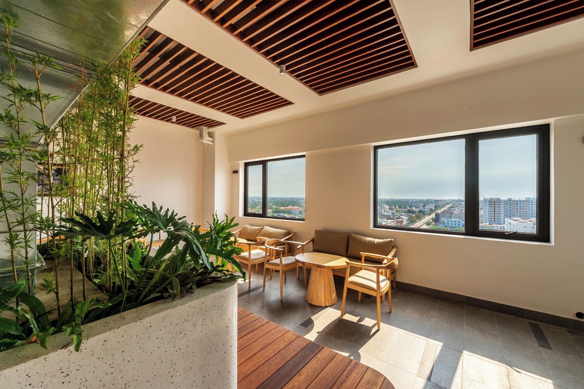 Ein modernes Interieur mit Holzbalkendecke, großen Fenstern und einer Sitzecke mit Blick auf die Stadt.