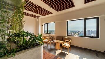 Ein modernes Interieur mit Holzbalkendecke, großen Fenstern und einer Sitzecke mit Blick auf die Stadt.