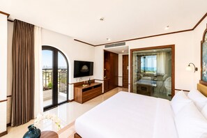 A hotel room with a large bed, a TV, a balcony, and a glass-enclosed shower area.