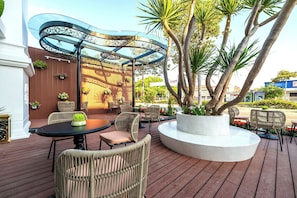 Un espace patio aménagé avec des meubles en osier, une table ronde et un pot décoratif contenant un arbre.