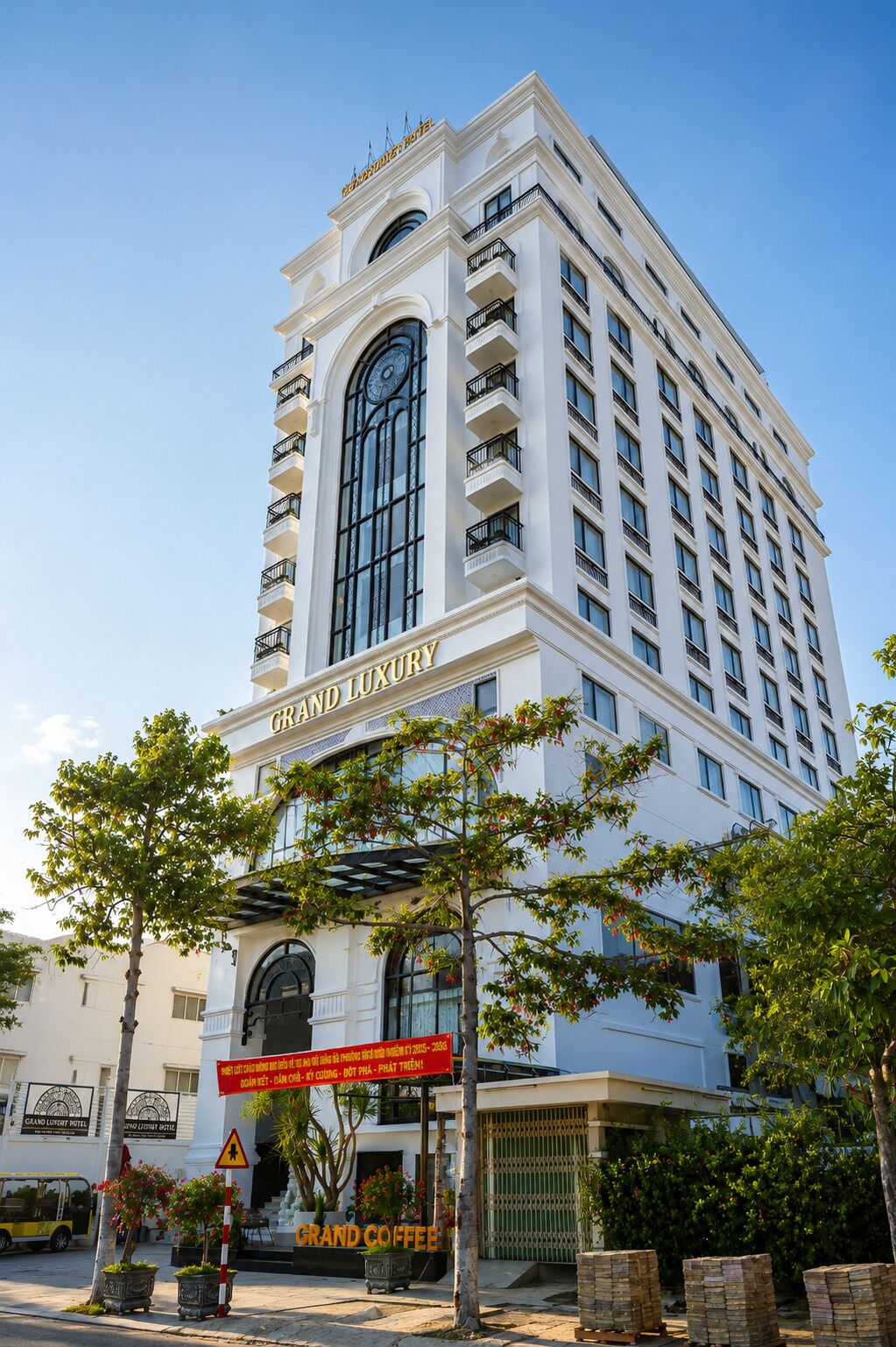 Un hotel de varios pisos con un cartel llamativo que dice 'GRAND LUXURY HOTEL' y un amplio ventanal en arco.