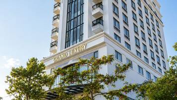 Un hotel de varios pisos con un cartel llamativo que dice 'GRAND LUXURY HOTEL' y un amplio ventanal en arco.