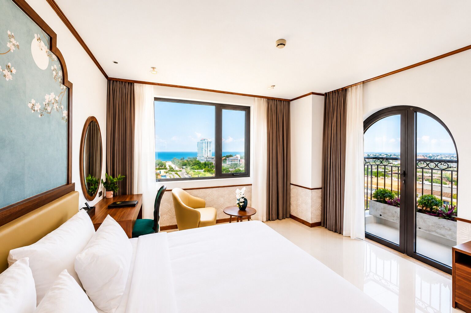 Habitación de hotel con una cama grande, un escritorio, una silla, una mesita y vistas a la ciudad y al océano.