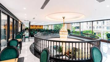 A restaurant with a circular seating area, a chandelier, and a view of the city.