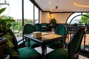 Un restaurante con una mesa para dos, sillas tapizadas de verde y vistas al exterior a través de amplios ventanales.