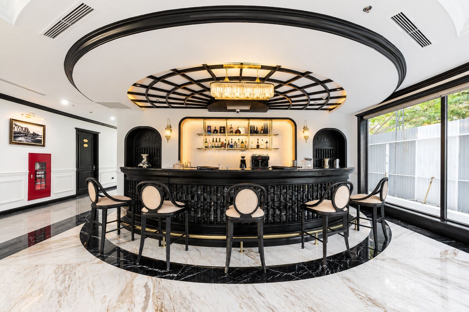 A bar area with a circular layout, marble flooring, and a central chandelier.