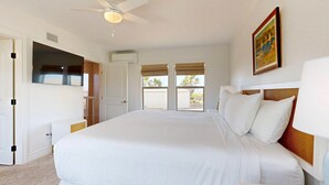 A hotel room with a large bed, a ceiling fan, a TV, and a painting on the wall. - Private Pool, Pet Friendly, 7 Minute Walk to the Beach (Port Aransas)
