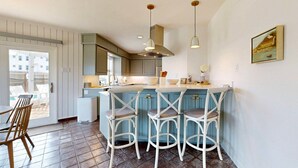 A modern kitchen with a central island, bar stools, pendant lighting, and a view of the outside. - Private Pool, Pet Friendly, 7 Minute Walk to the Beach (Port Aransas)