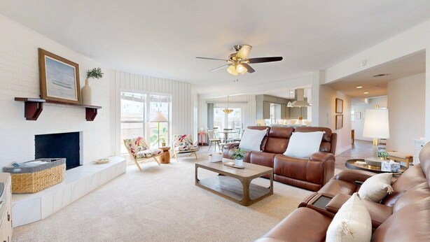 A spacious living room with a fireplace, leather sofa, and a dining area with a chandelier. - Private Pool, Pet Friendly, 7 Minute Walk to the Beach (Port Aransas)