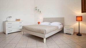 Ein Schlafzimmer mit Bett, Nachttisch, Lampe und Kommode.