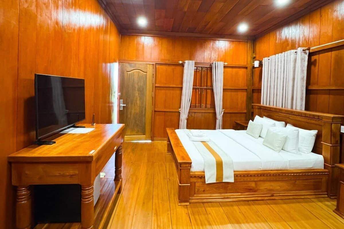 A wooden-paneled bedroom with a bed, a TV, and a nightstand.