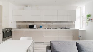 A modern kitchen with white cabinets, a microwave, a kettle, and a gas stove. - GuestHost - MM5 Isola Bright Apartment (Milano)