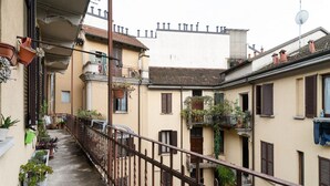 A narrow alleyway with balconies, potted plants, and a metal railing. - GuestHost - MM5 Isola Bright Apartment (Milano)
