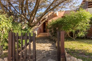 Un chemin de pierres menant à un bâtiment doté d’une porte en bois.