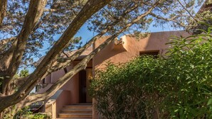 A building with a staircase leading to a door, surrounded by trees and vegetation.