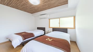 A hotel room with two beds, a wooden ceiling, an air conditioning unit, a window, and a nightstand.