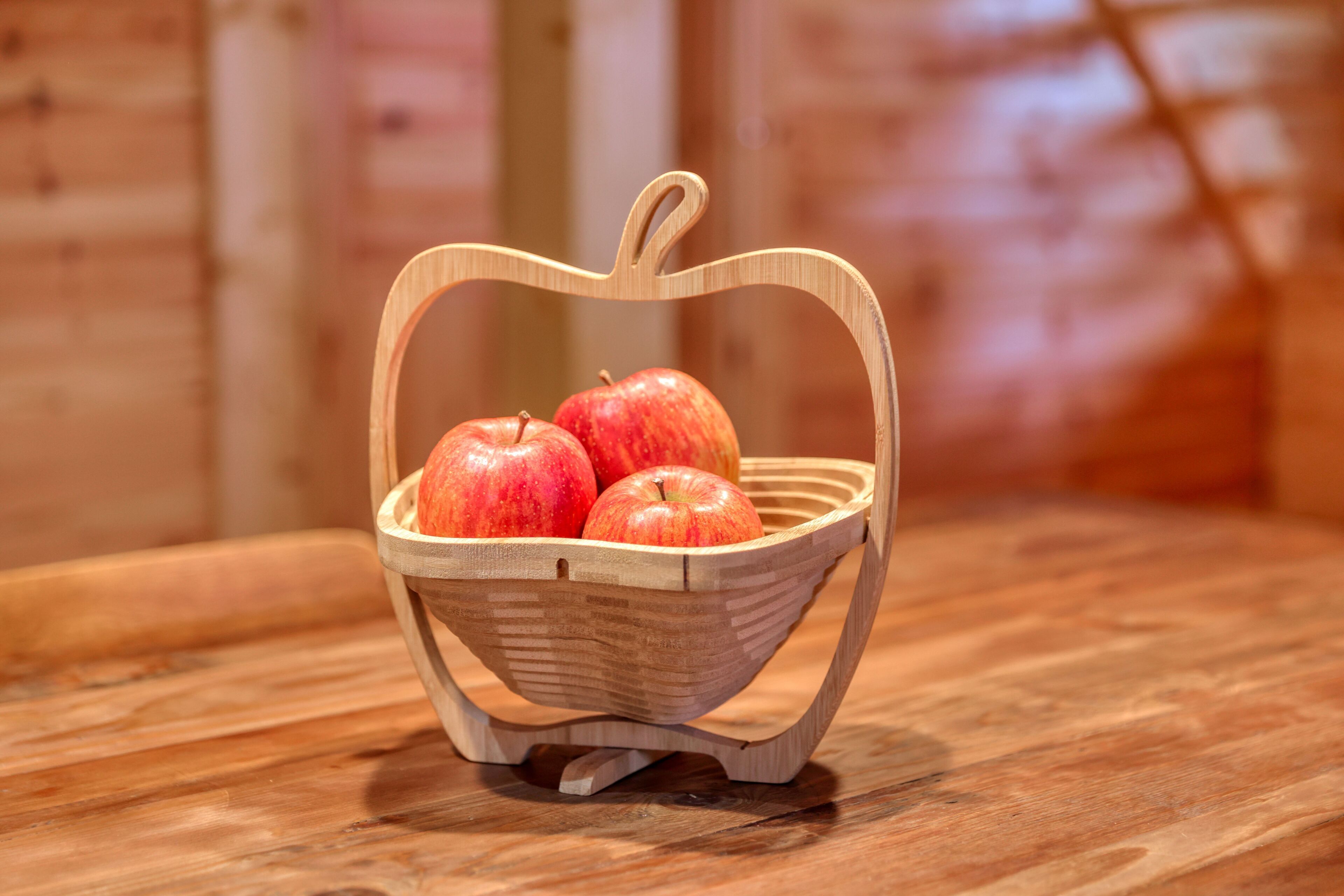 Un panier en bois avec une anse, posé sur une table en bois.