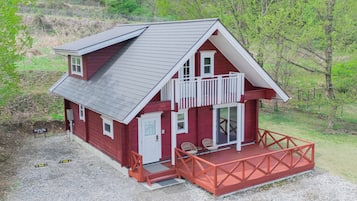 A two-story red building with a balcony, a gravel driveway, and a fenced yard.