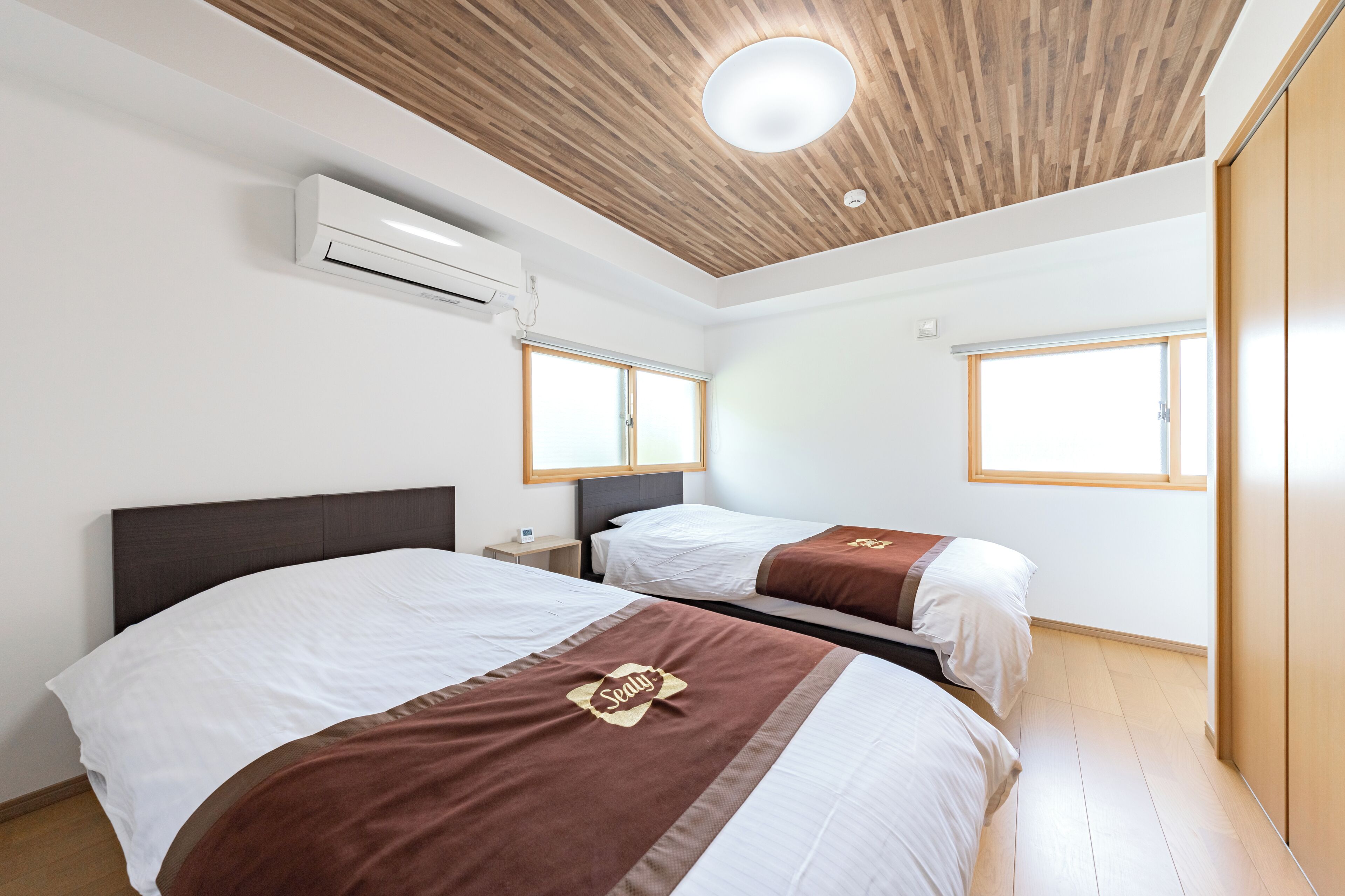 Habitación de hotel con dos camas, techo de madera, aire acondicionado y una ventana.