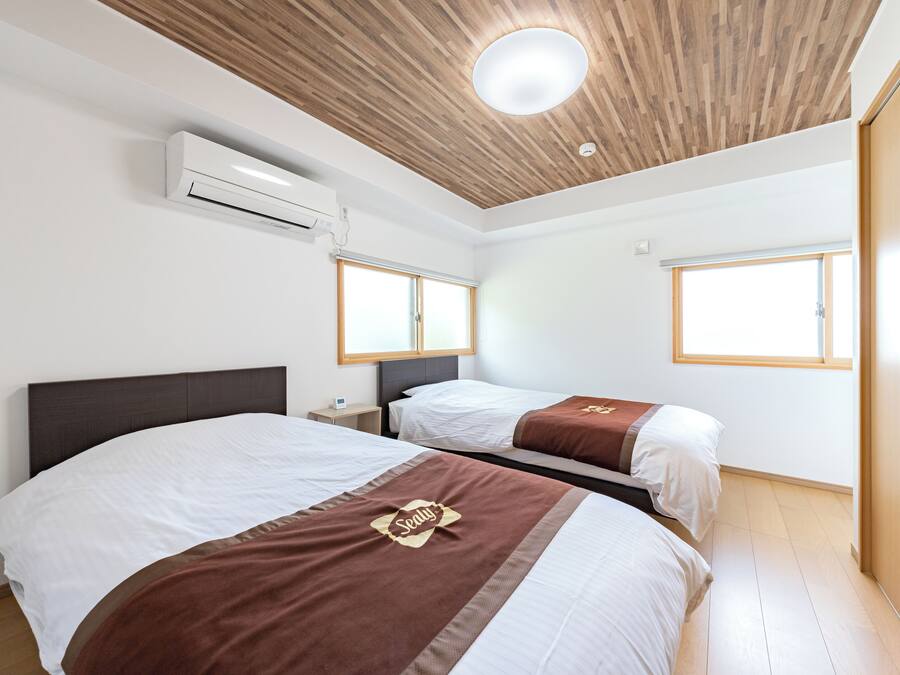 Habitación de hotel con dos camas, techo de madera, aire acondicionado y una ventana.