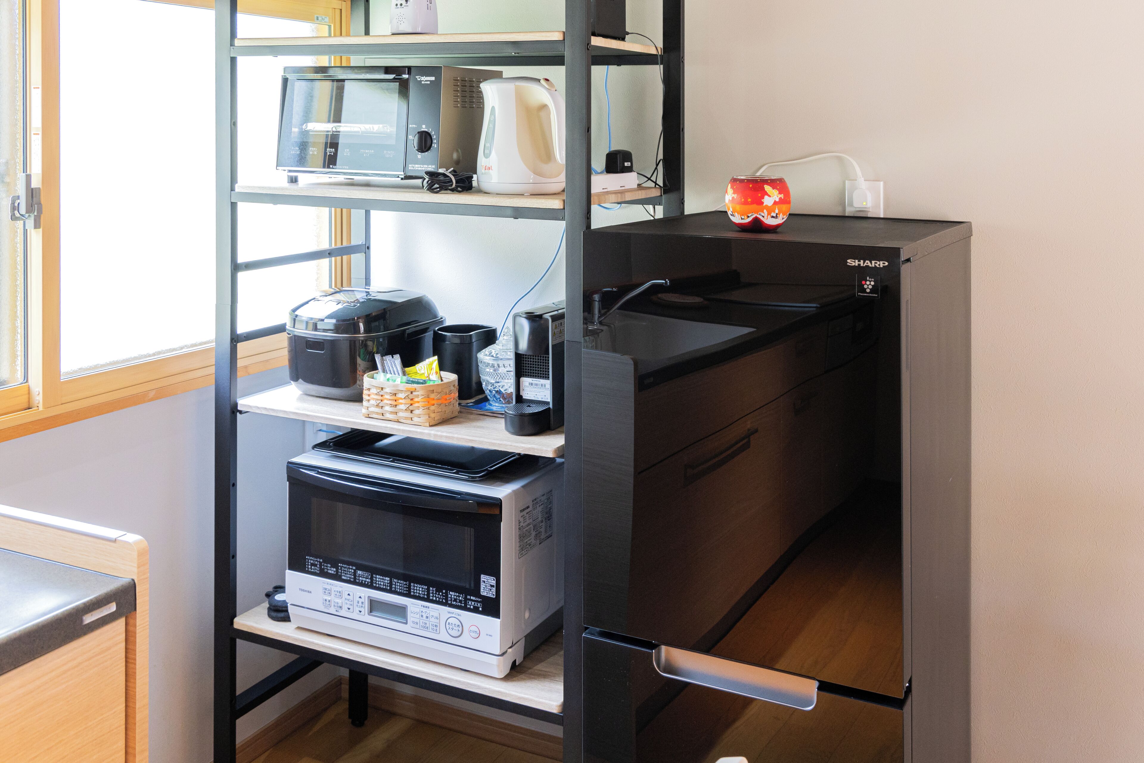 Una cocina equipada con microondas, cafetera y un refrigerador Sharp.