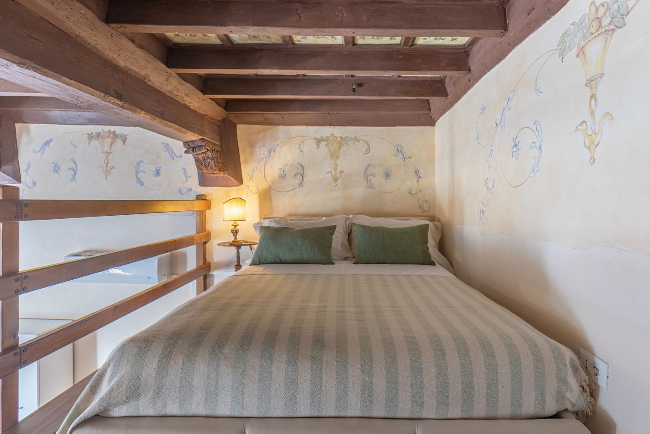 A bedroom with a bed, wooden headboard, and a nightstand with a lamp.